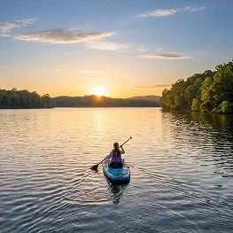 Kayaker paddling across Weiss Lake at sunset