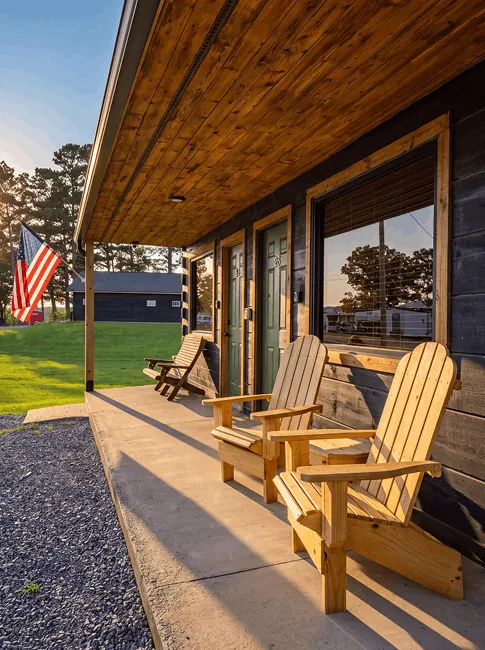 Adirondack chairs along the covered porch outside the lakeside rooms at sunset