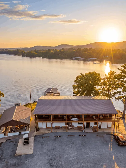 The restaurant building and its covered decks above Weiss Lake at sunset, seen from the air
