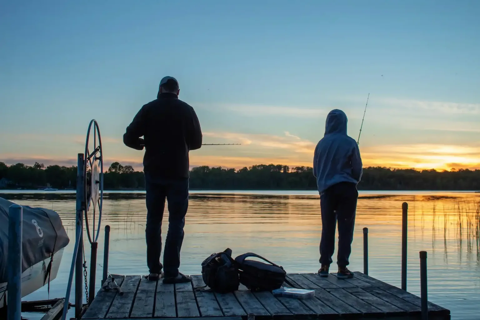 Two anglers casting from the end of a dock on Weiss Lake at sunset